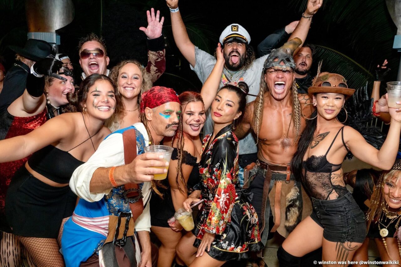 A fun group of friends dressed in costumes at Tiki's Grill & Bar's Halloween party with a DJ and live bands.